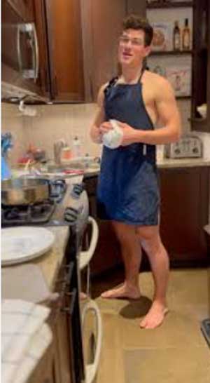 young man in a kitchen wearing only an apron
